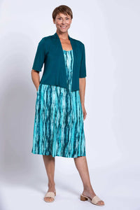 Woman in aqua streak dress styled with a teal shrug, showcasing versatile outfit