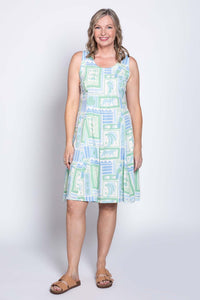 Woman wearing sleeveless Arden dress with tropical green and blue print, front view