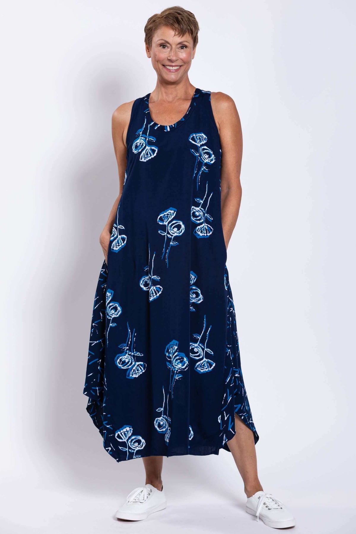 Woman smiling while wearing navy blue tank dress with blue and white floral print