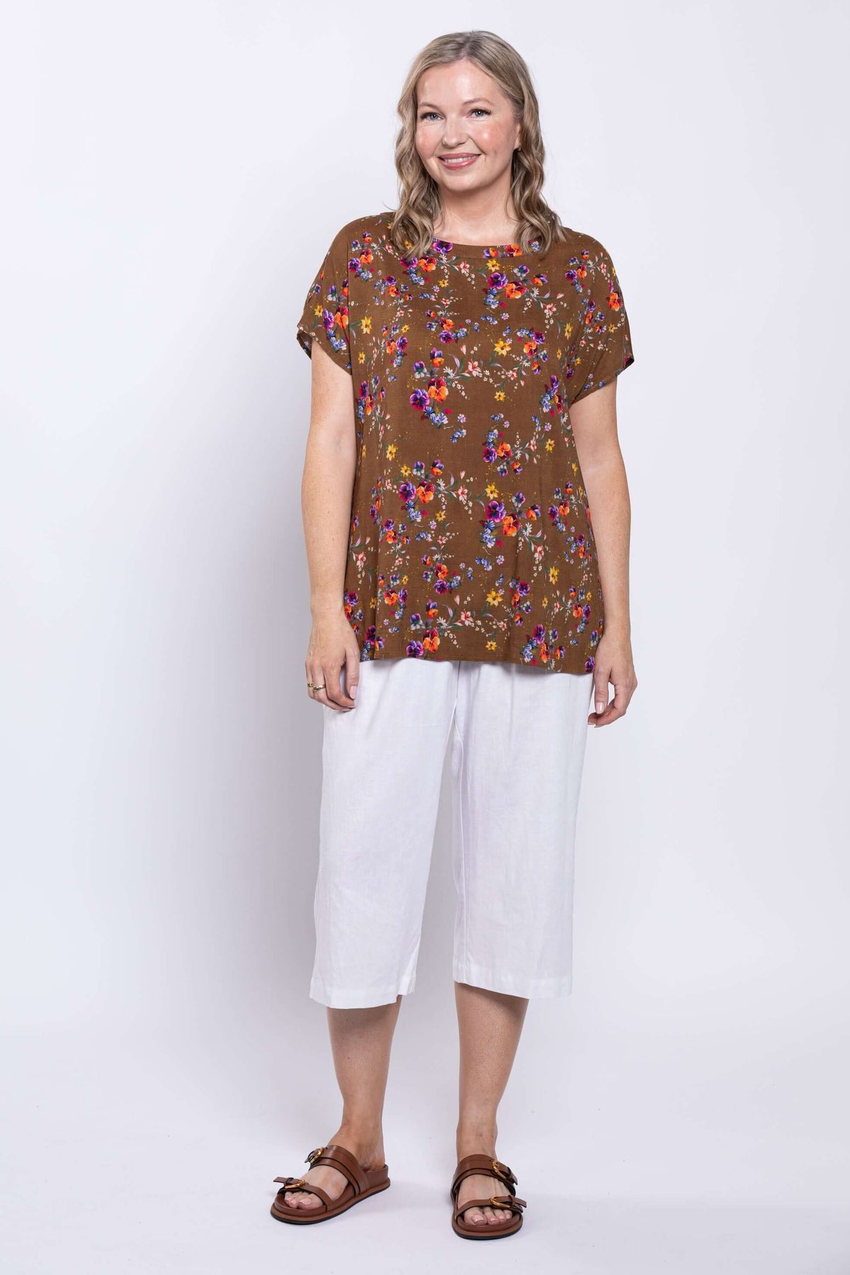 Front facing model in brown top with colorful florals, styled with white culottes