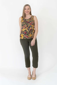 Woman smiling in sleeveless marigold batik tank top and green pants, frontal full-body view
