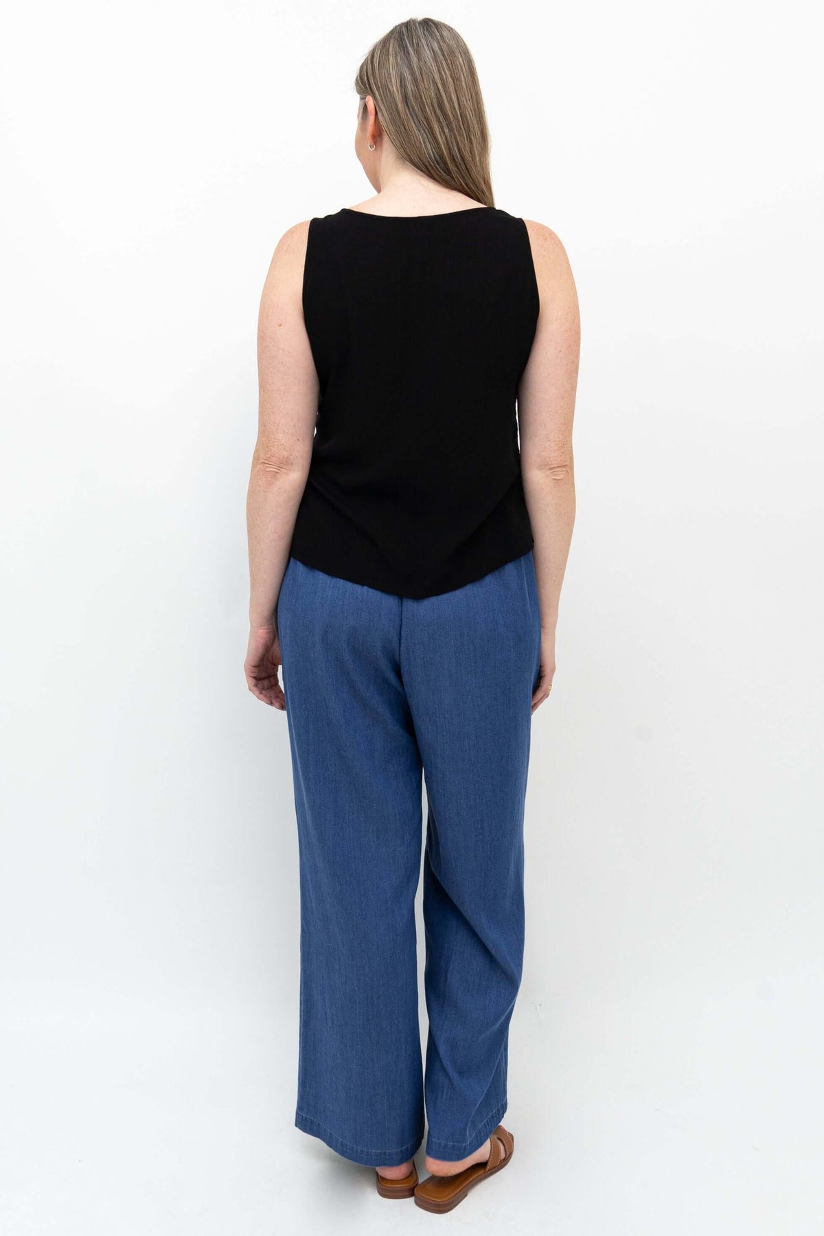 Rear view of woman wearing wide-leg blue denim Tencel pants and black sleeveless top