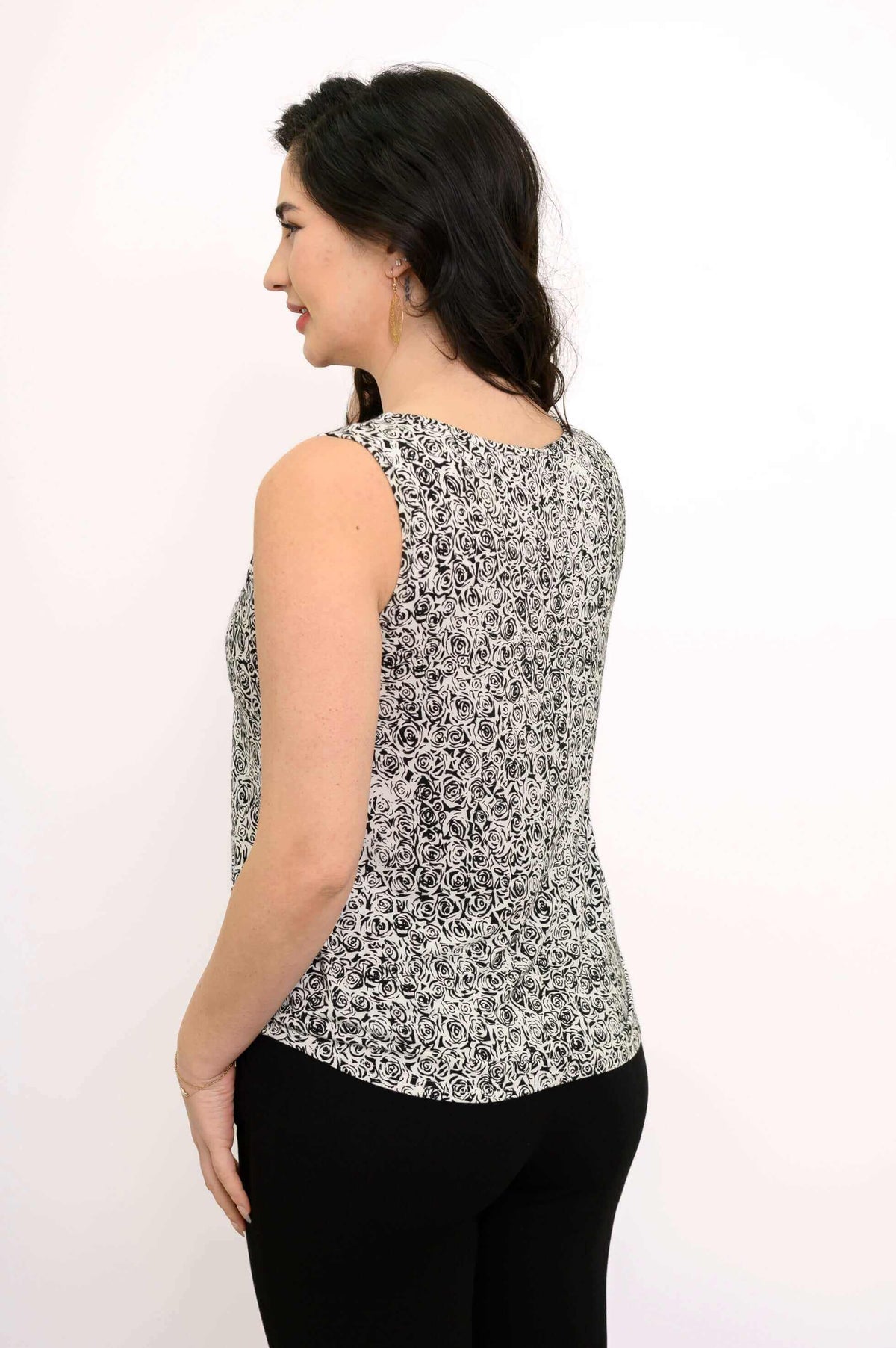 Back view of woman wearing a black and white small rose print tank top with black pants