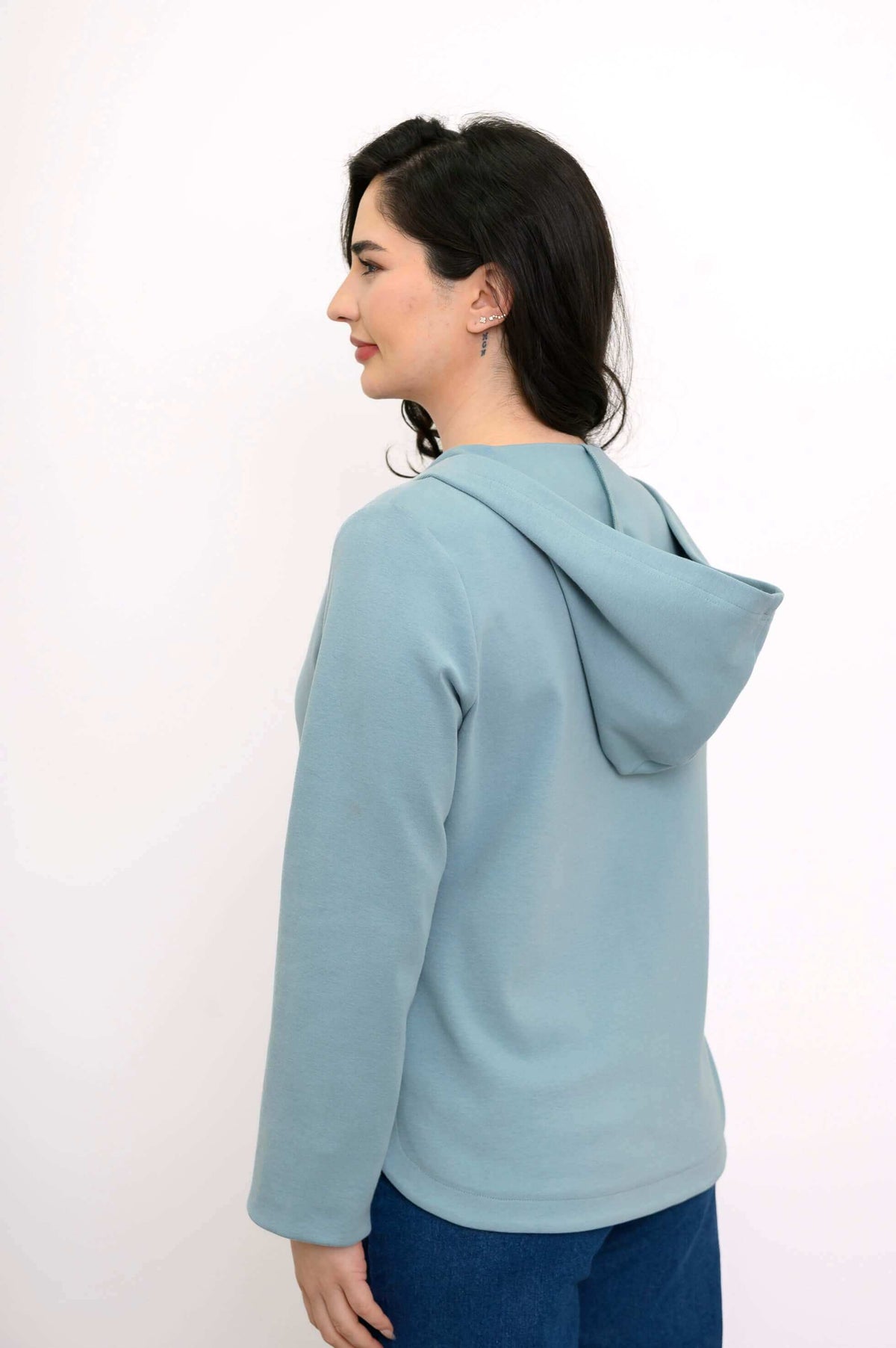 Back and side view of woman in a light blue hoodie showing the hood and relaxed fit