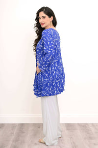 Back angled view of woman wearing blue Maria tunic with white abstract print