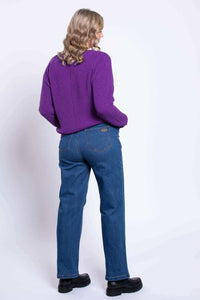 Back view of a woman wearing blue straight leg jeans with a purple sweater.