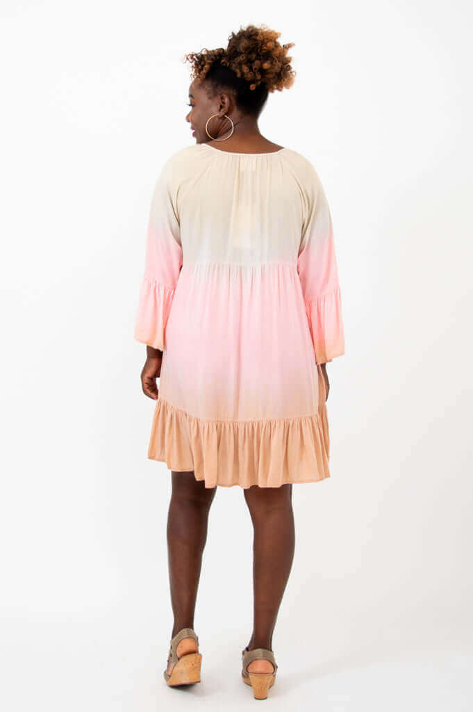 Back view of a woman in a peach and pink ombre knee-length dress