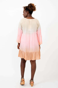 Back view of a woman in a peach and pink ombre knee-length dress
