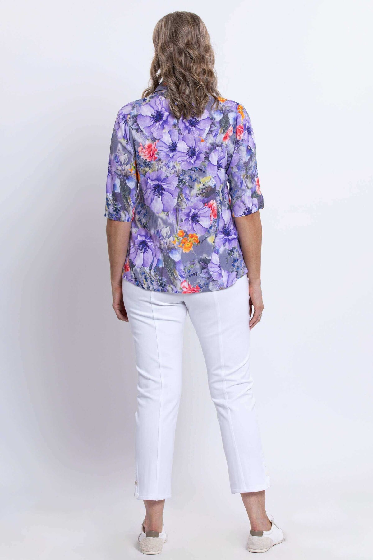 Back view of model in Lorine purple floral blouse with white pants
