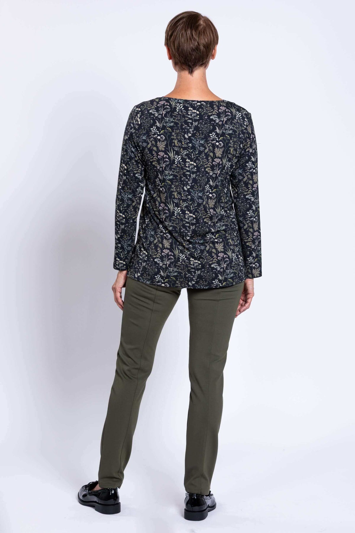 Back view of woman in a dark floral long sleeve top and olive pants