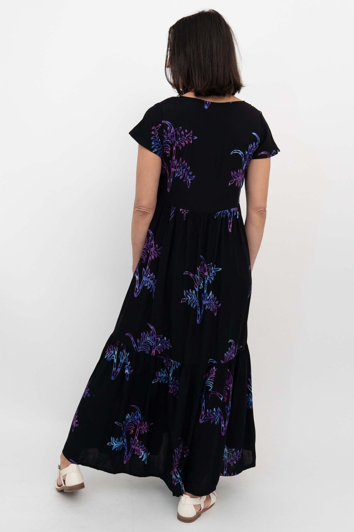 Back view of black maxi dress with tiered skirt and colorful botanical print