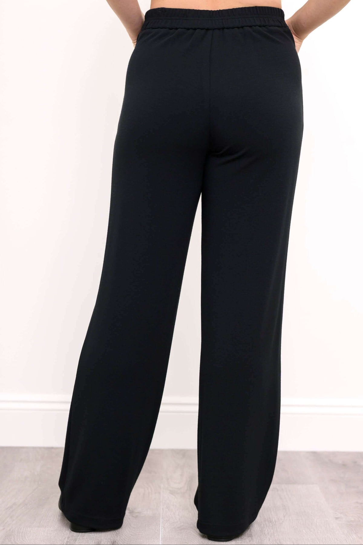 Back view of black straight leg pants with elastic waistband