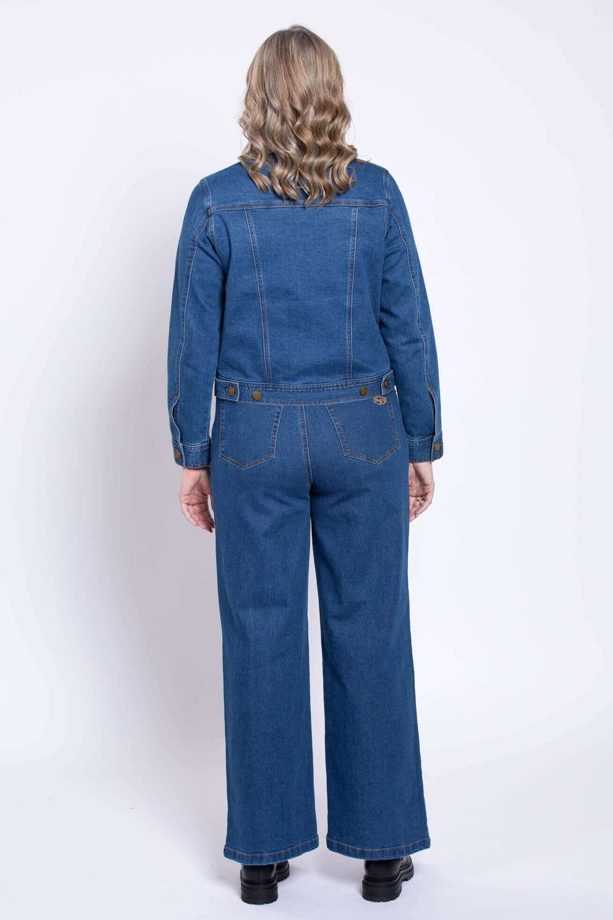 Back view of woman wearing blue denim jacket and wide-leg jeans
