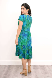Back view of woman wearing a green and blue dress featuring a tiered skirt and short sleeves