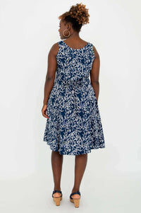 Back view of model wearing a navy and white A-line summer dress with tie-belt