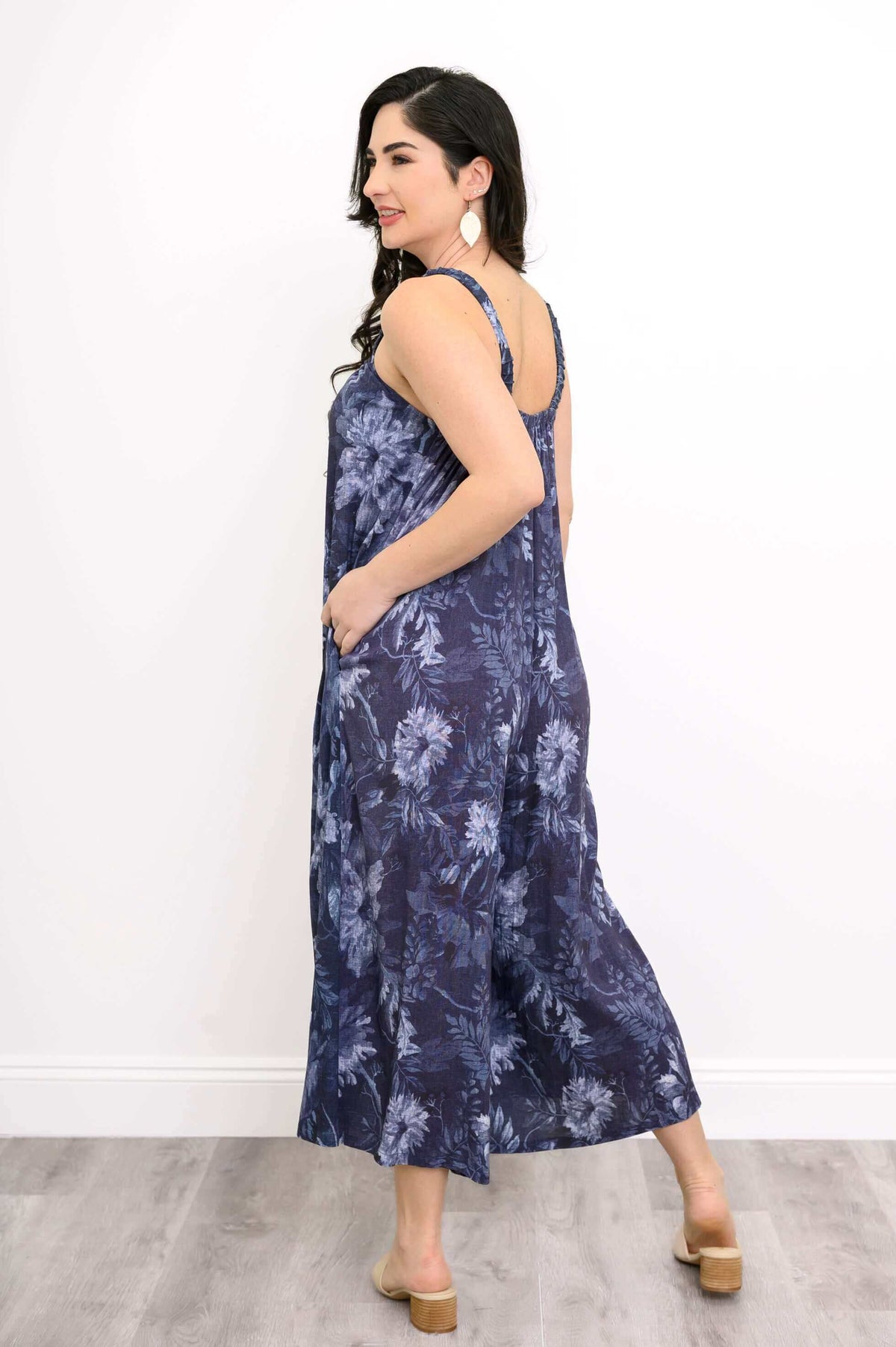 Back view of woman in a navy floral jumpsuit showing wide straps and pockets