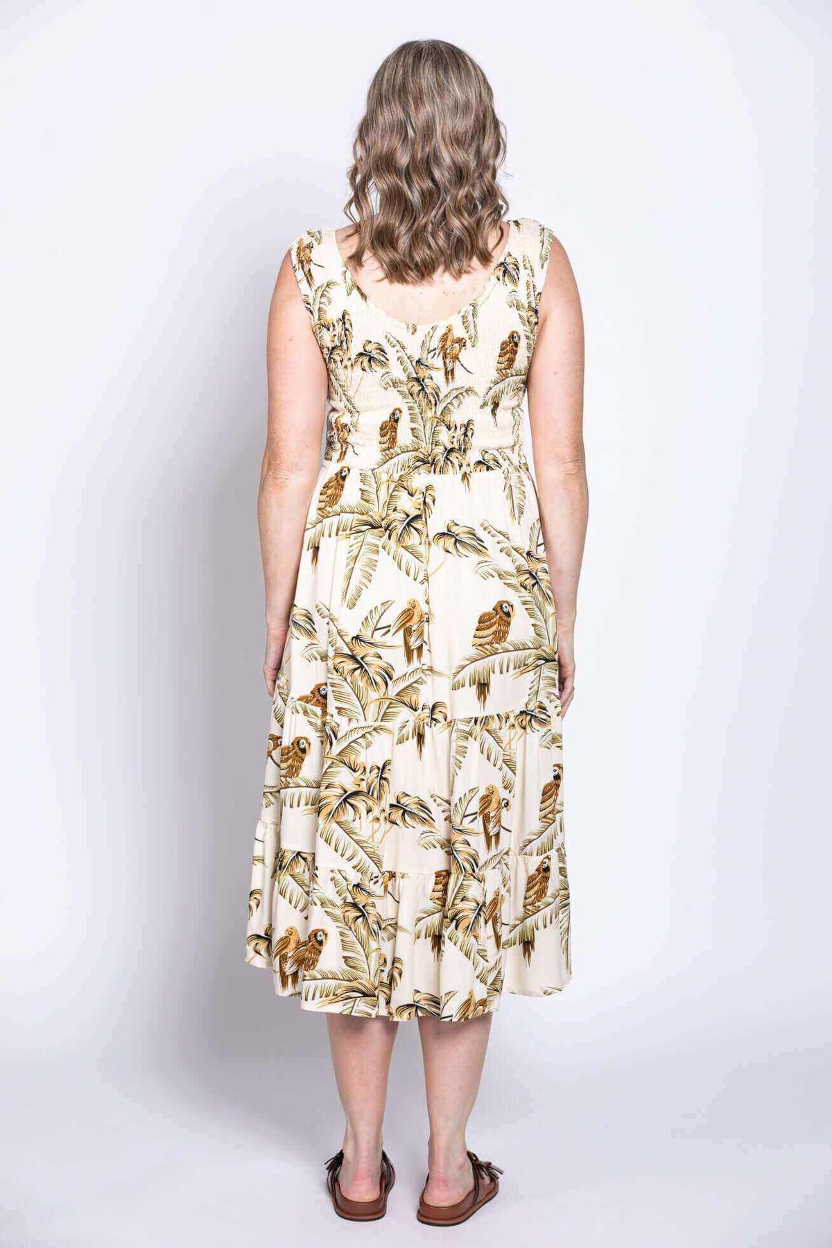 Back view of woman in sleeveless tropical print midi dress, showing length and fit