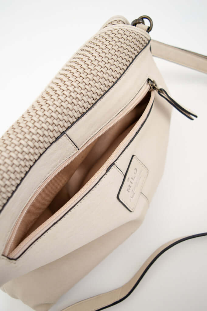 Close-up of back zip pocket and Milo Italy label on ivory bag with strap