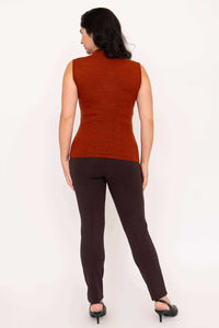 Back view of woman in sleeveless rust merino wool sweater and brown pants