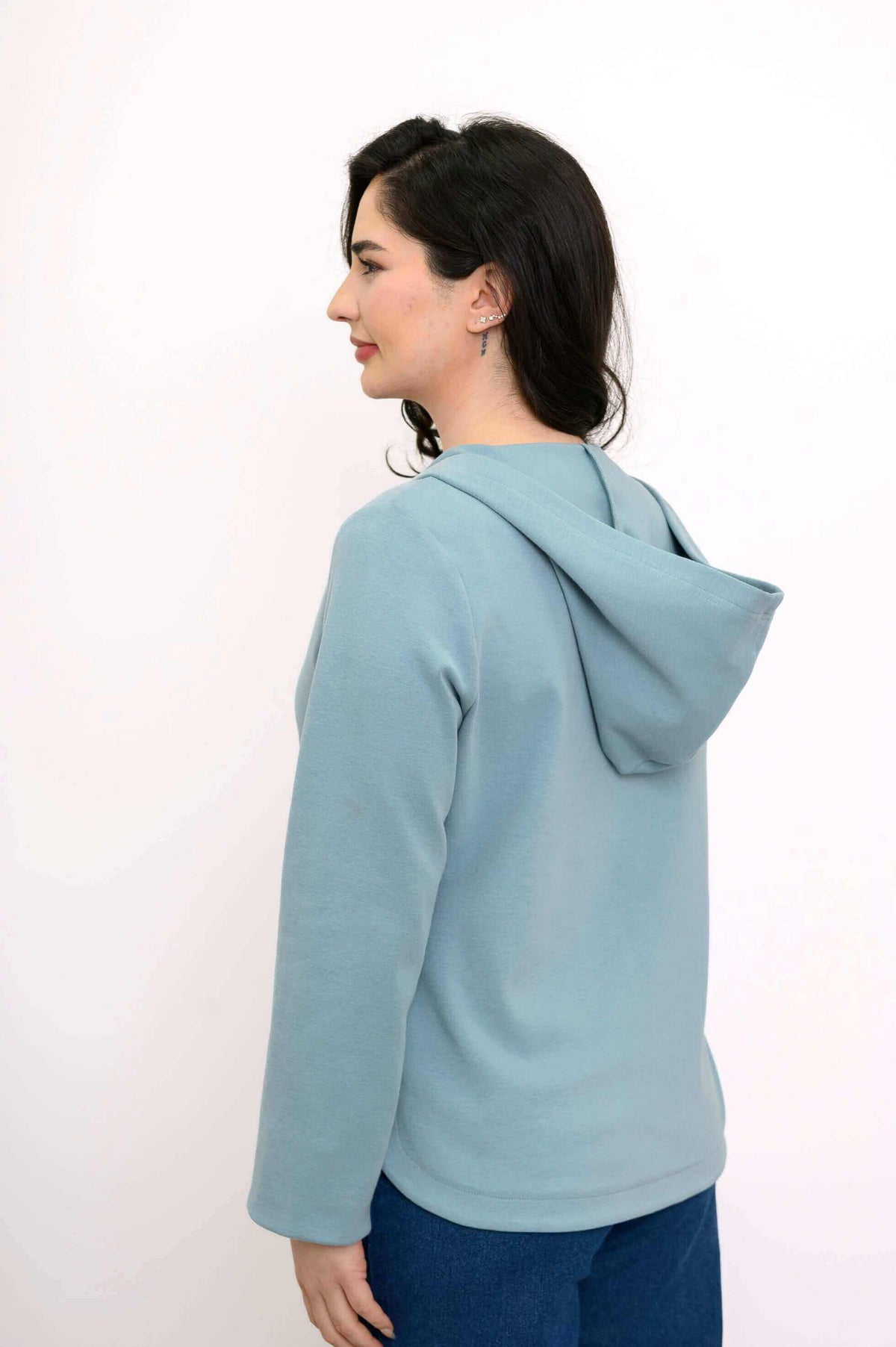 Back side view of woman wearing light blue hoodie jacket with hood down