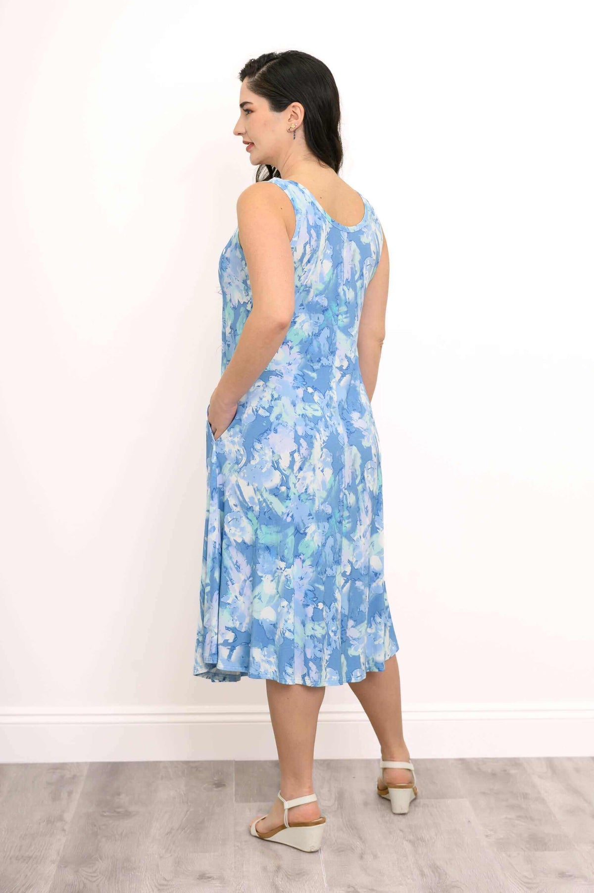 Woman in blue abstract tank dress showing back and side with hands in pockets