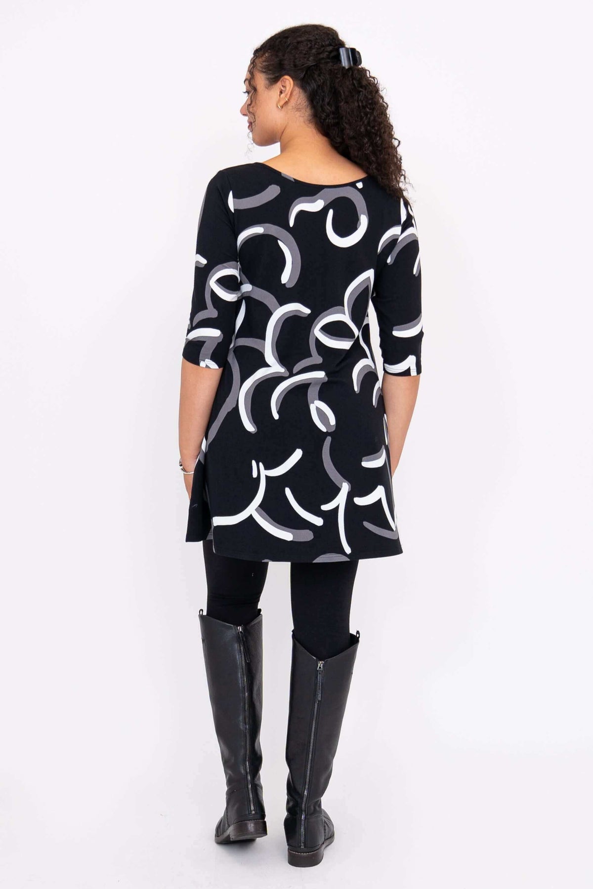 Back view of model showcasing black A-line dress with abstract white and gray design