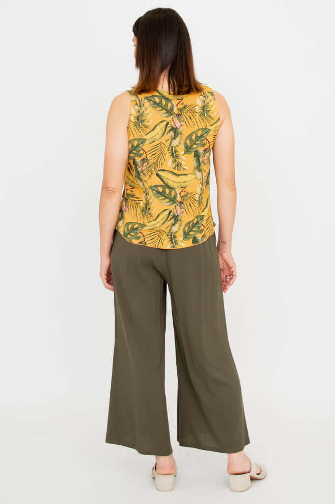 Back view of woman wearing yellow tropical tank top and olive green wide-leg pants