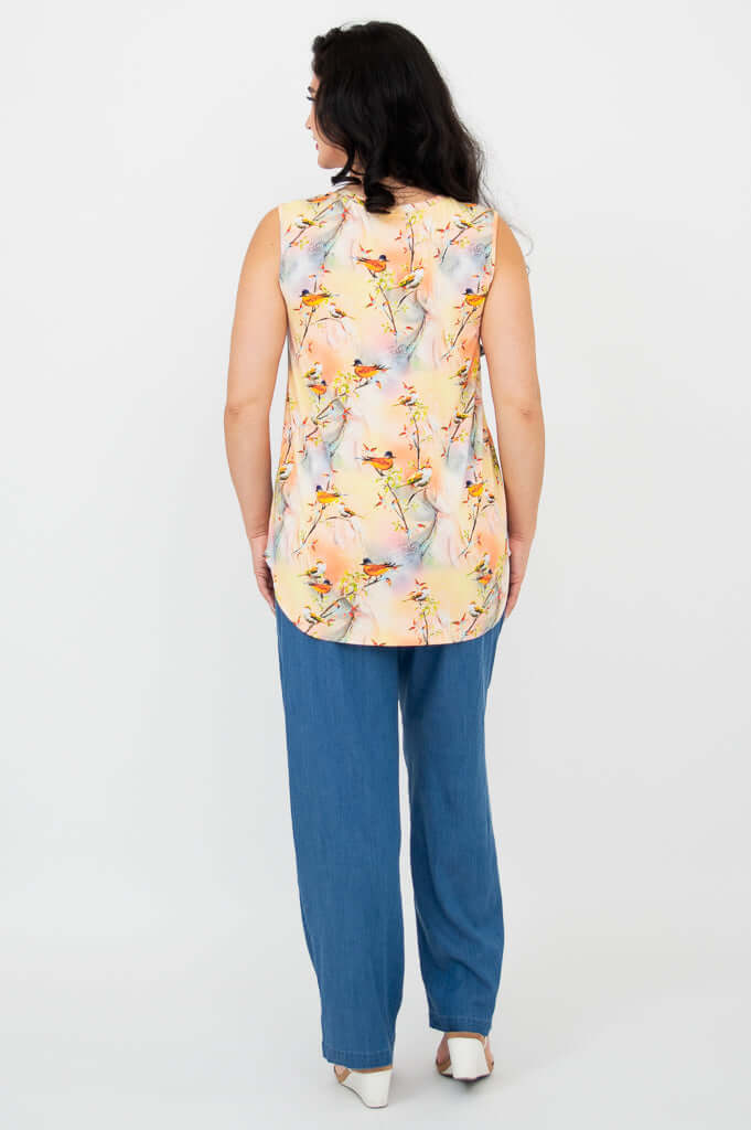 Back view of woman in sleeveless bird print bamboo top and blue pants