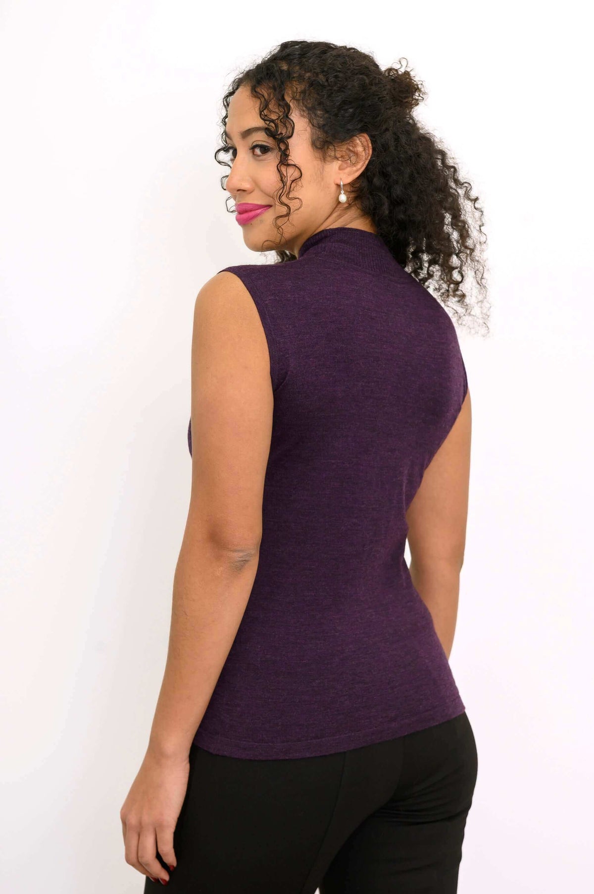 Back view of woman in sleeveless purple Merino wool mock neck sweater