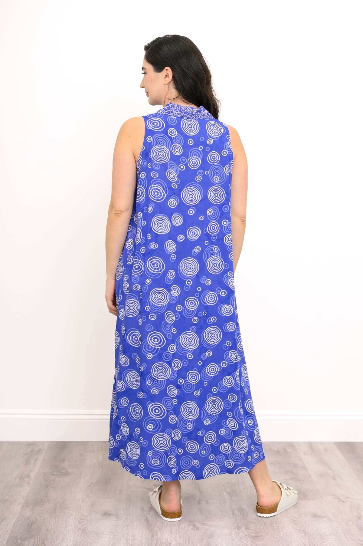 Back view of model wearing sleeveless A-line dress with white swirl print