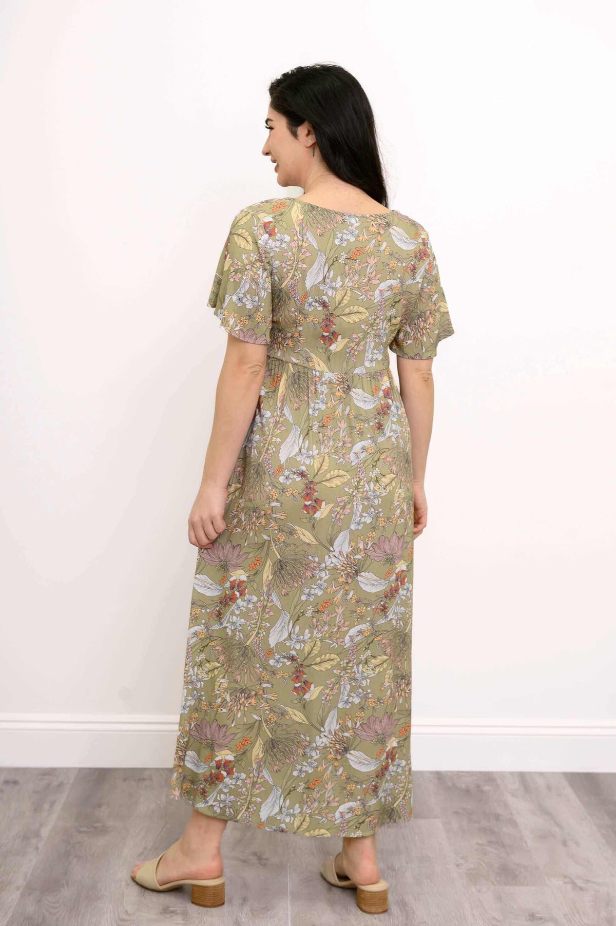 Rear view of a woman in a green floral maxi dress with short flutter sleeves