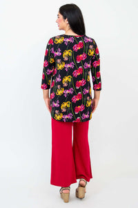 Back view of model wearing black chrysanthemum print top paired with red wide-leg pants