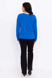 Back view of woman in blue boat neck long sleeve top and black pants