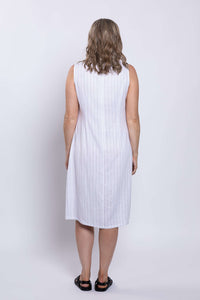 Back view of a woman in a white sleeveless dress with vertical stripes and black sandals