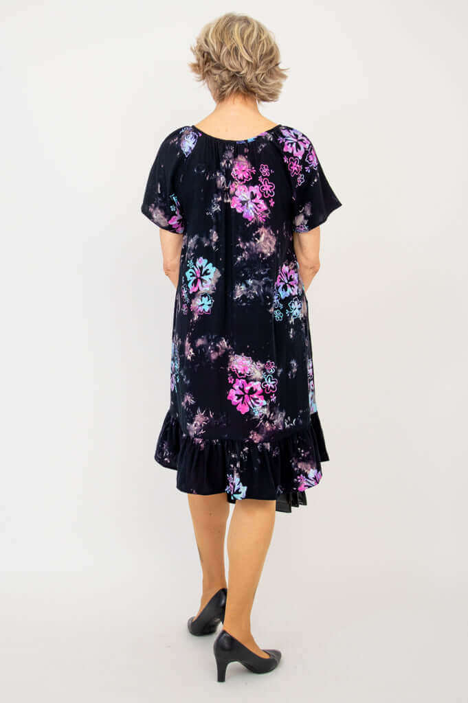 Back view of woman in black flower print dress with ruffled hem