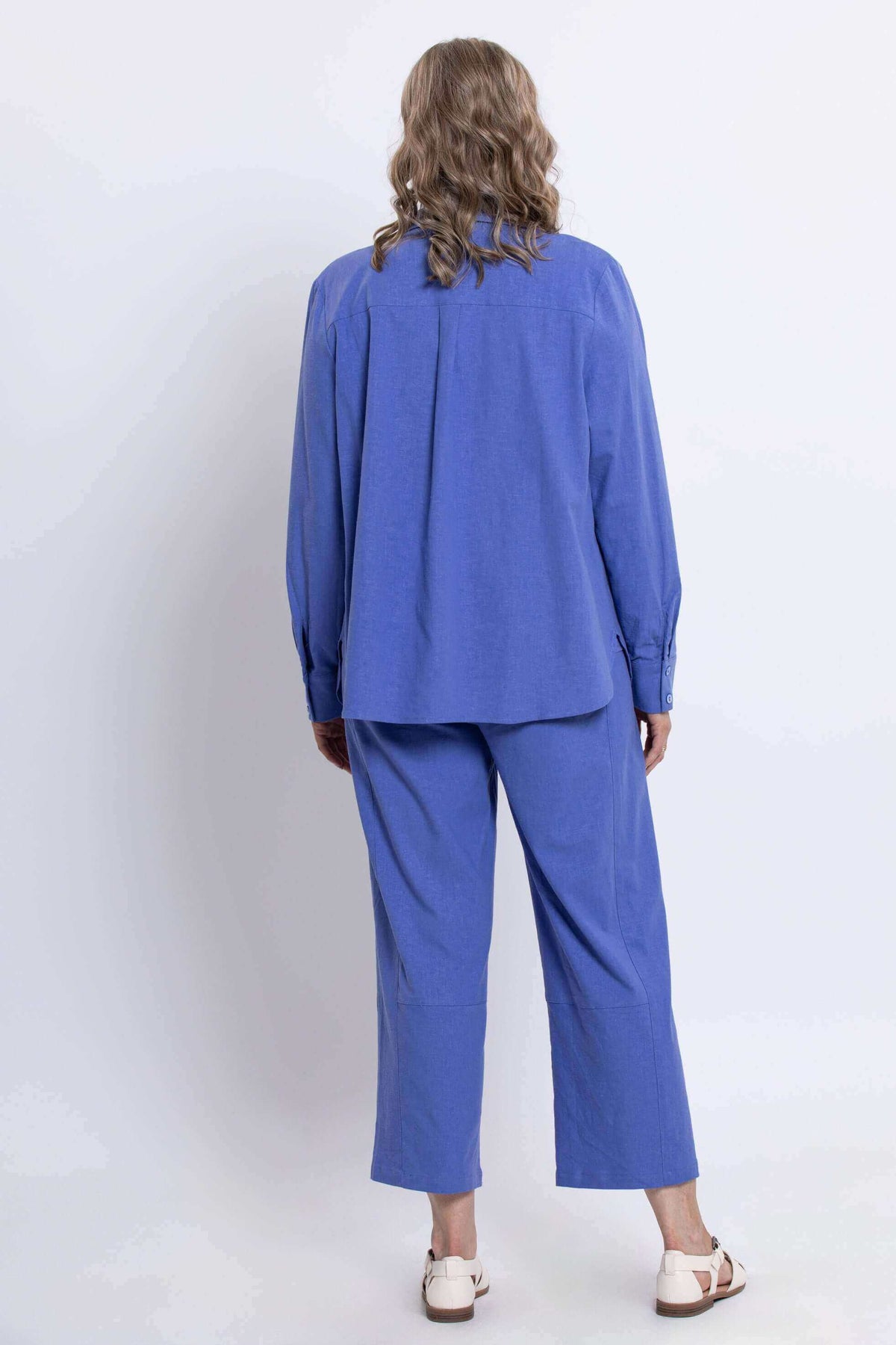 Back view of woman wearing an azure blue button-up shirt and matching pants