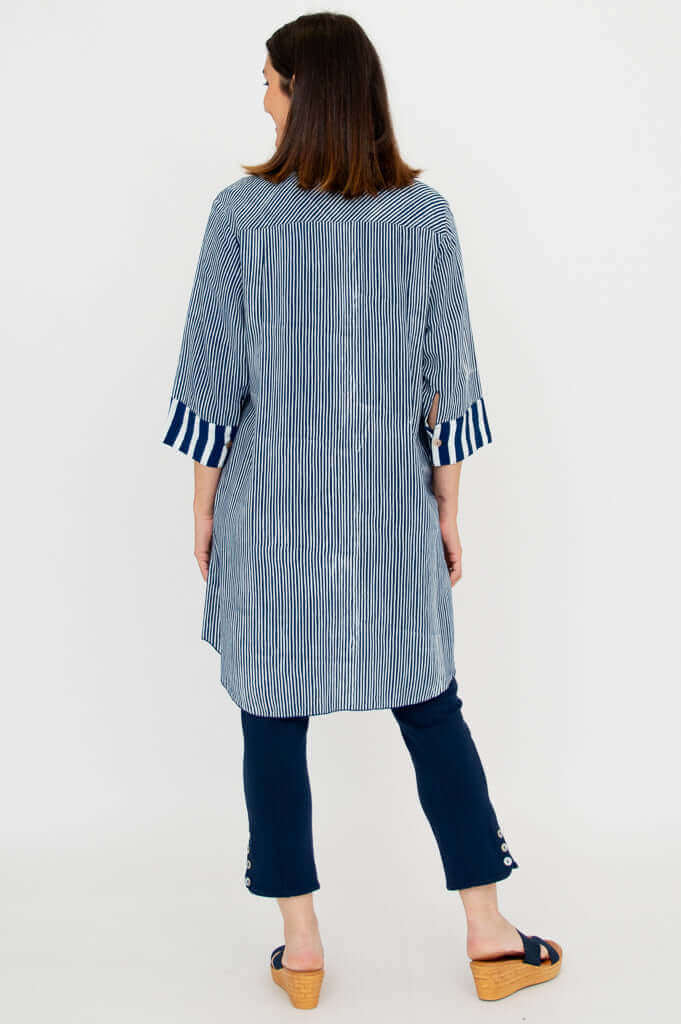 Back view of a woman wearing a blue and white striped oversized shirt with contrast cuffs
