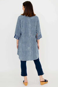 Back view of a woman wearing a blue and white striped oversized shirt with contrast cuffs