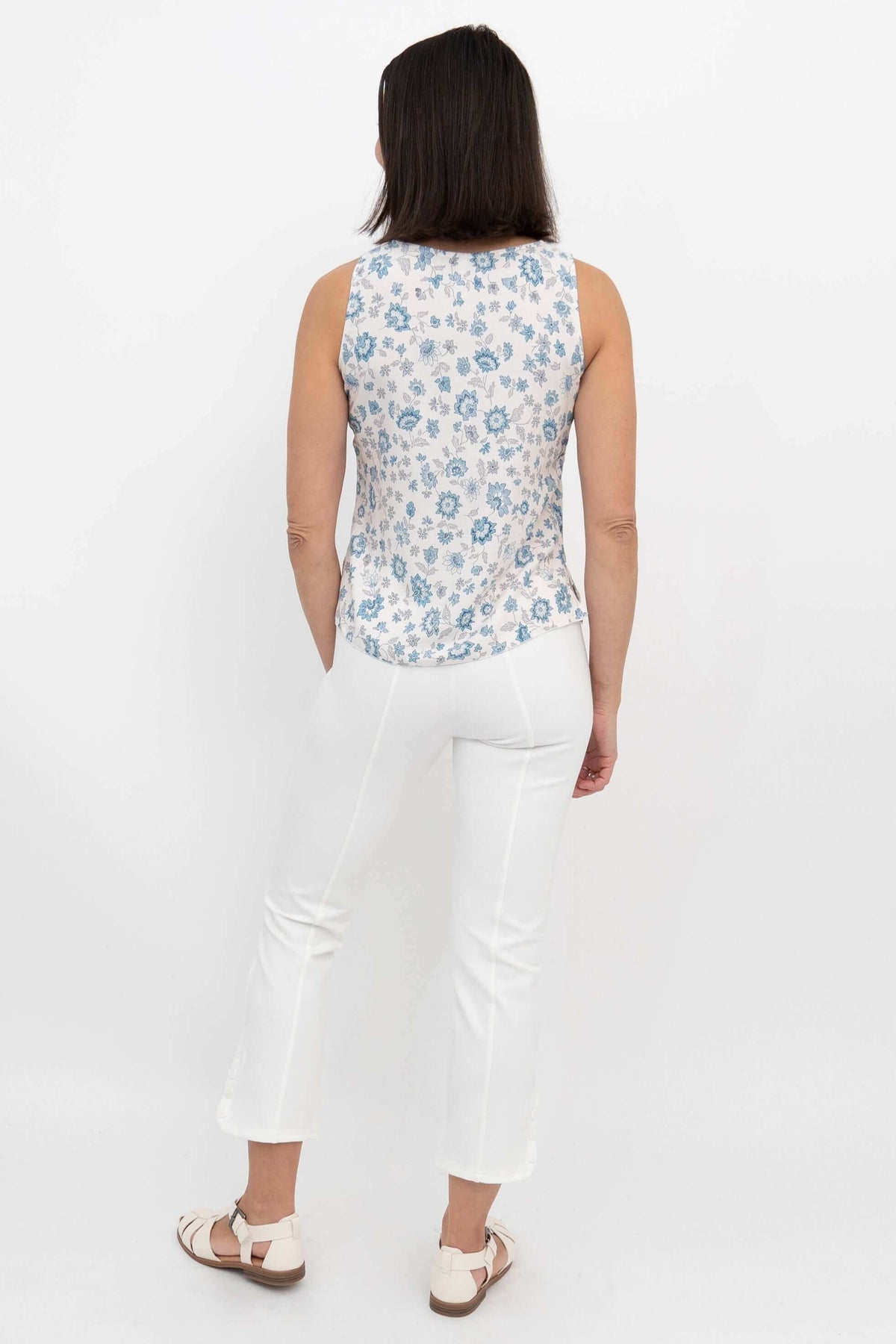 Back view of woman wearing a blue floral tank top and white pants