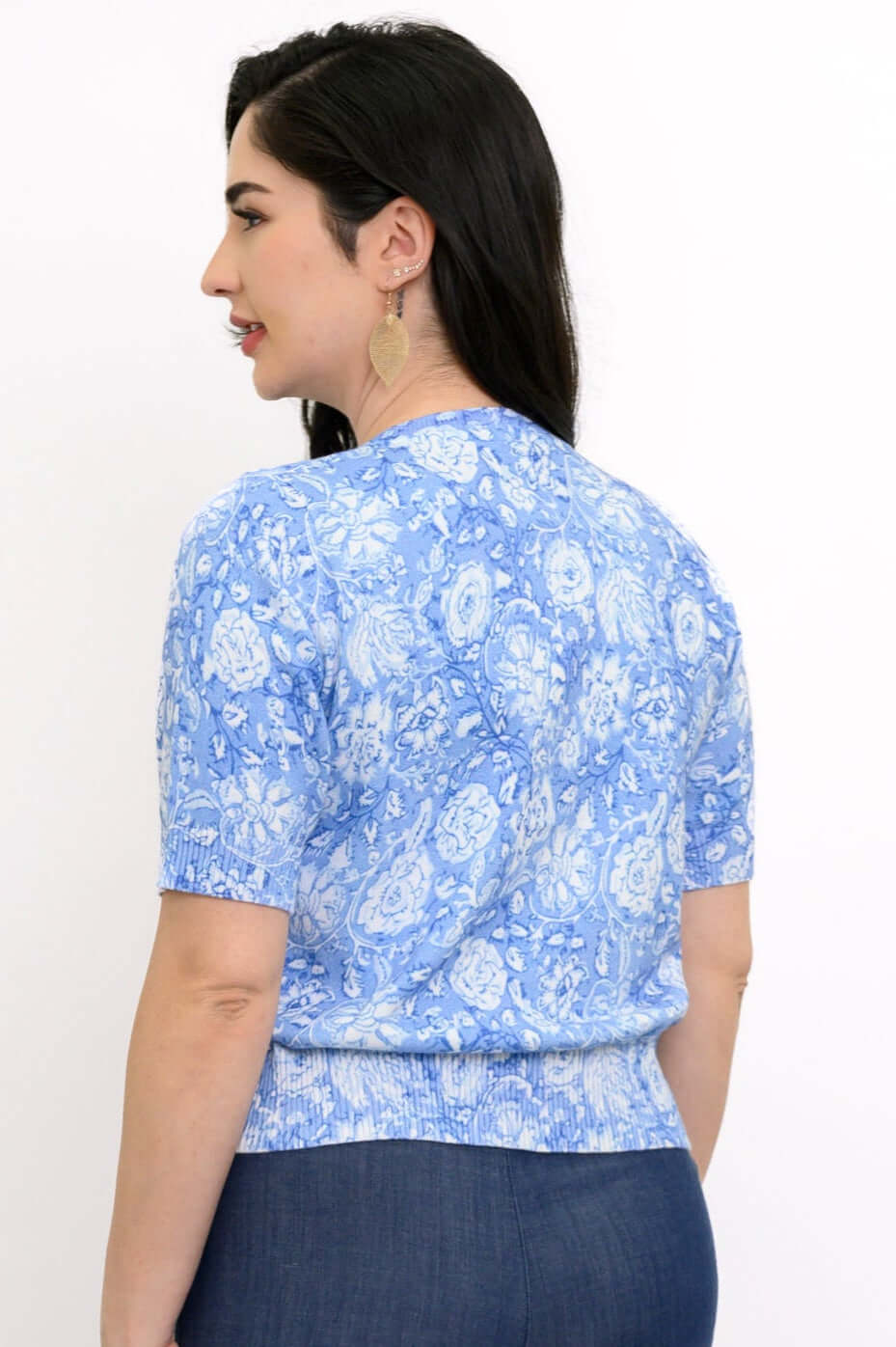 Back view of a blue floral short sleeve knit cardigan on a woman