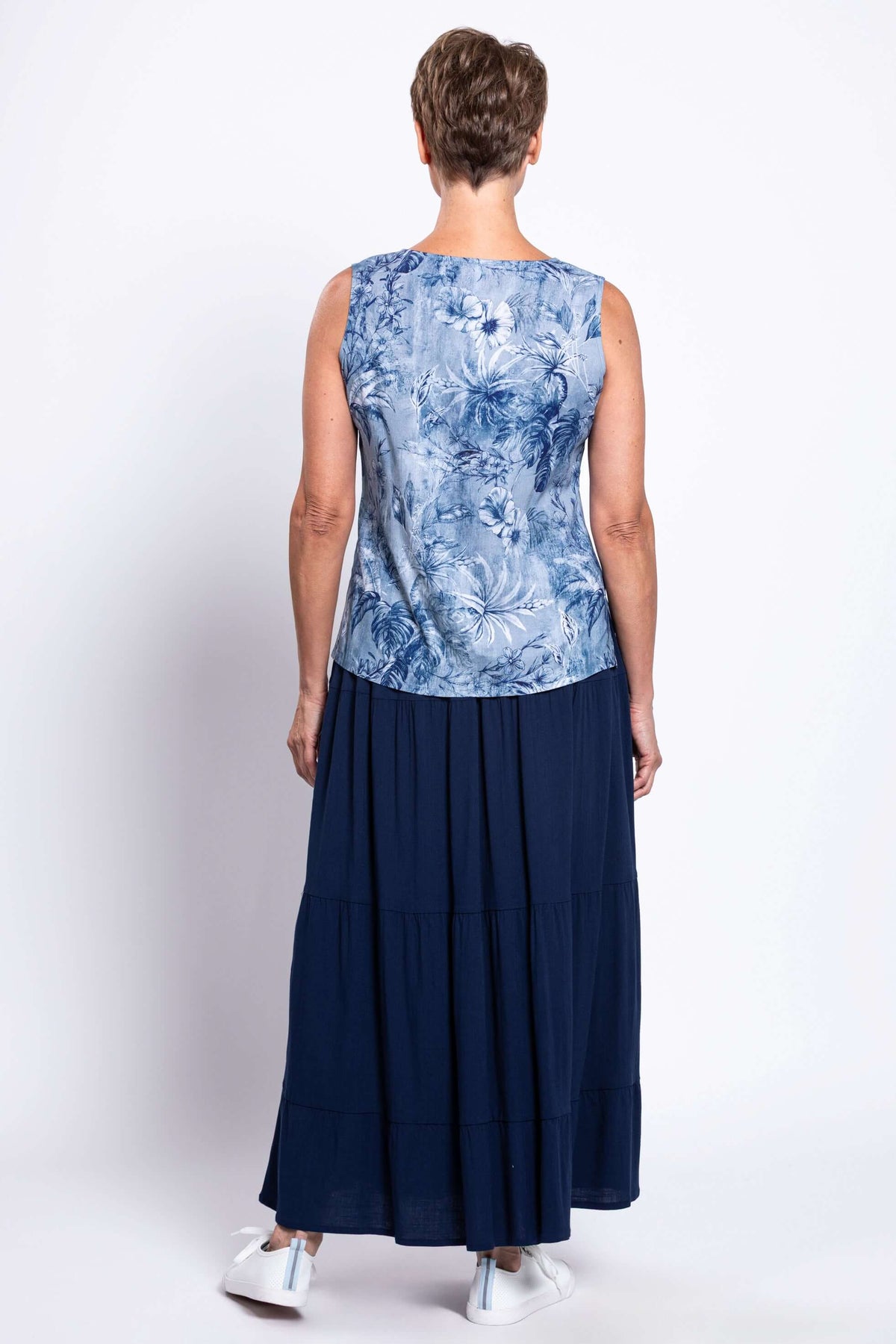 Back view of older woman in a blue floral tank top and navy maxi skirt