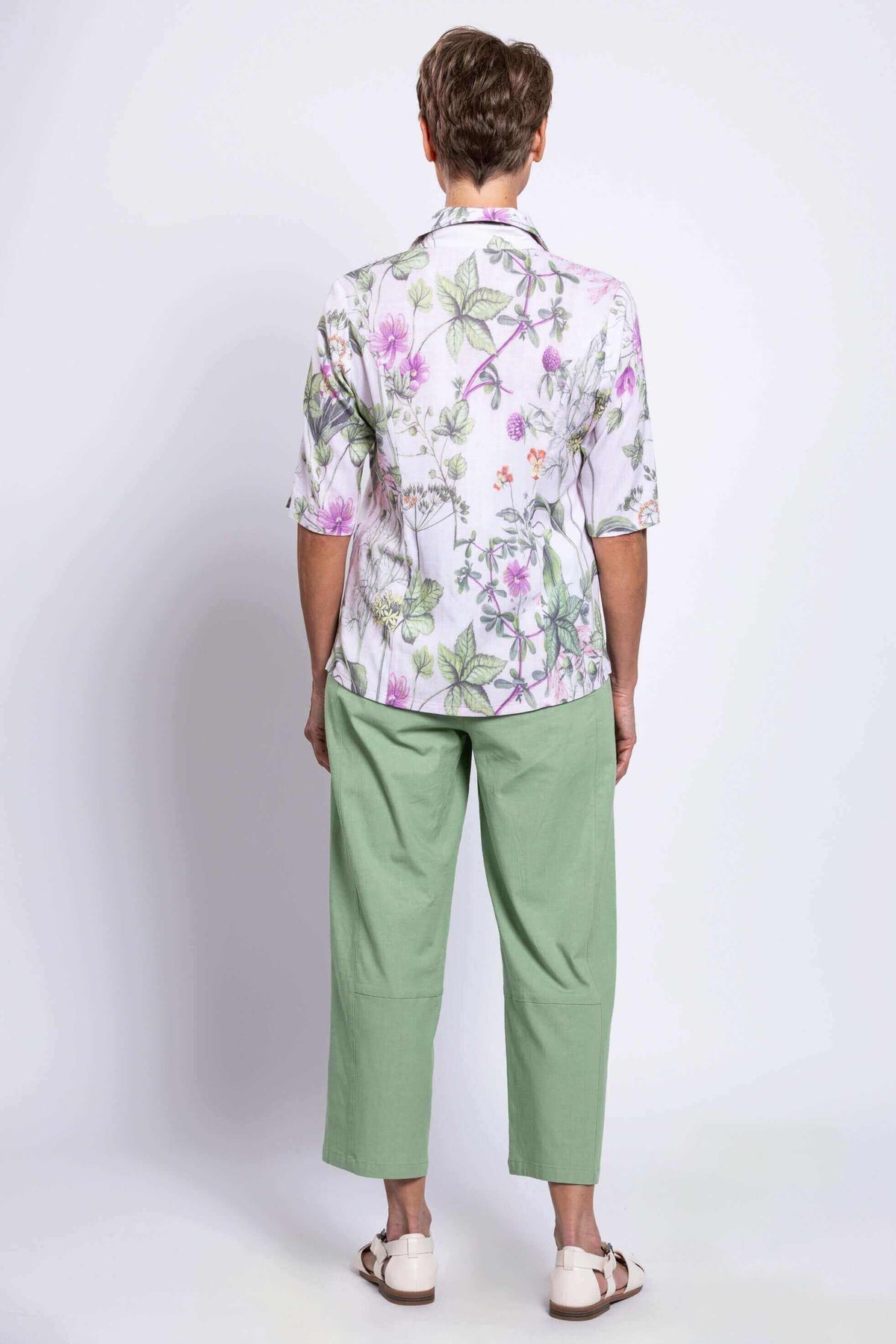 Back view of a woman in a floral print blouse and light green pants