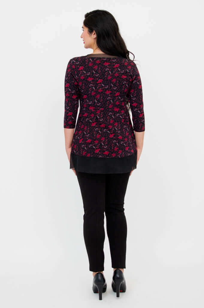 Back view of woman wearing floral mesh tunic and black fitted pants