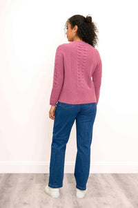 Full length shot of a woman wearing a pink cable knit cashmere cardigan with casual jeans and sneakers.