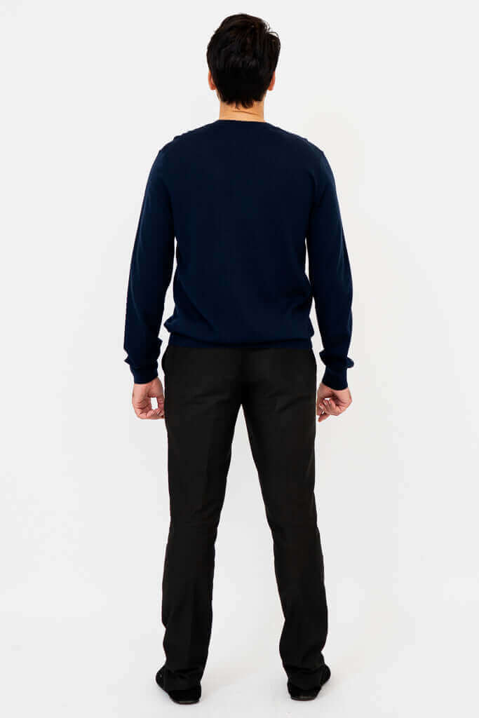 Back view of a man in a navy Merino wool sweater and black trousers