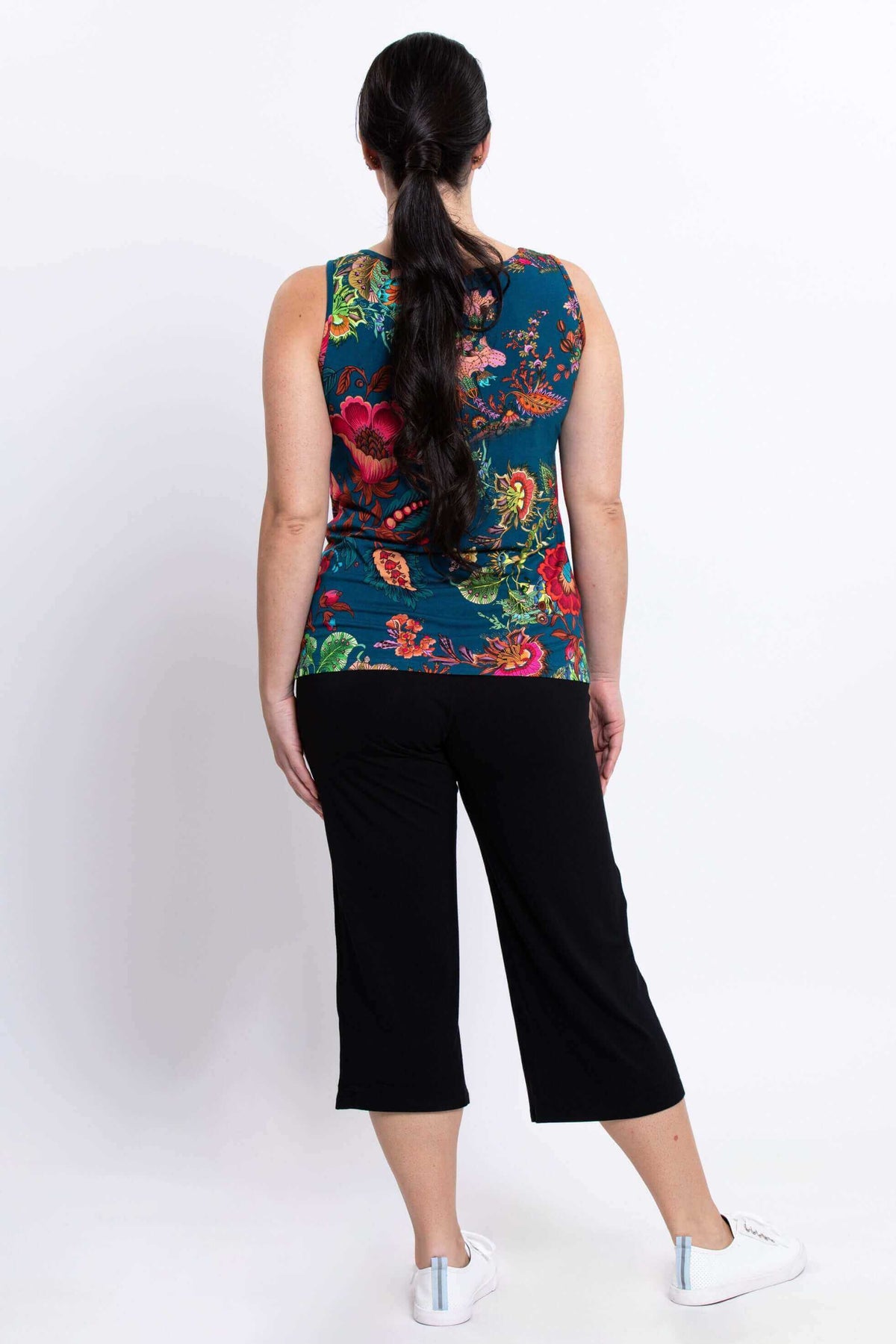 Back view of a woman wearing a teal floral Avalon bamboo tank top with long hair in a ponytail