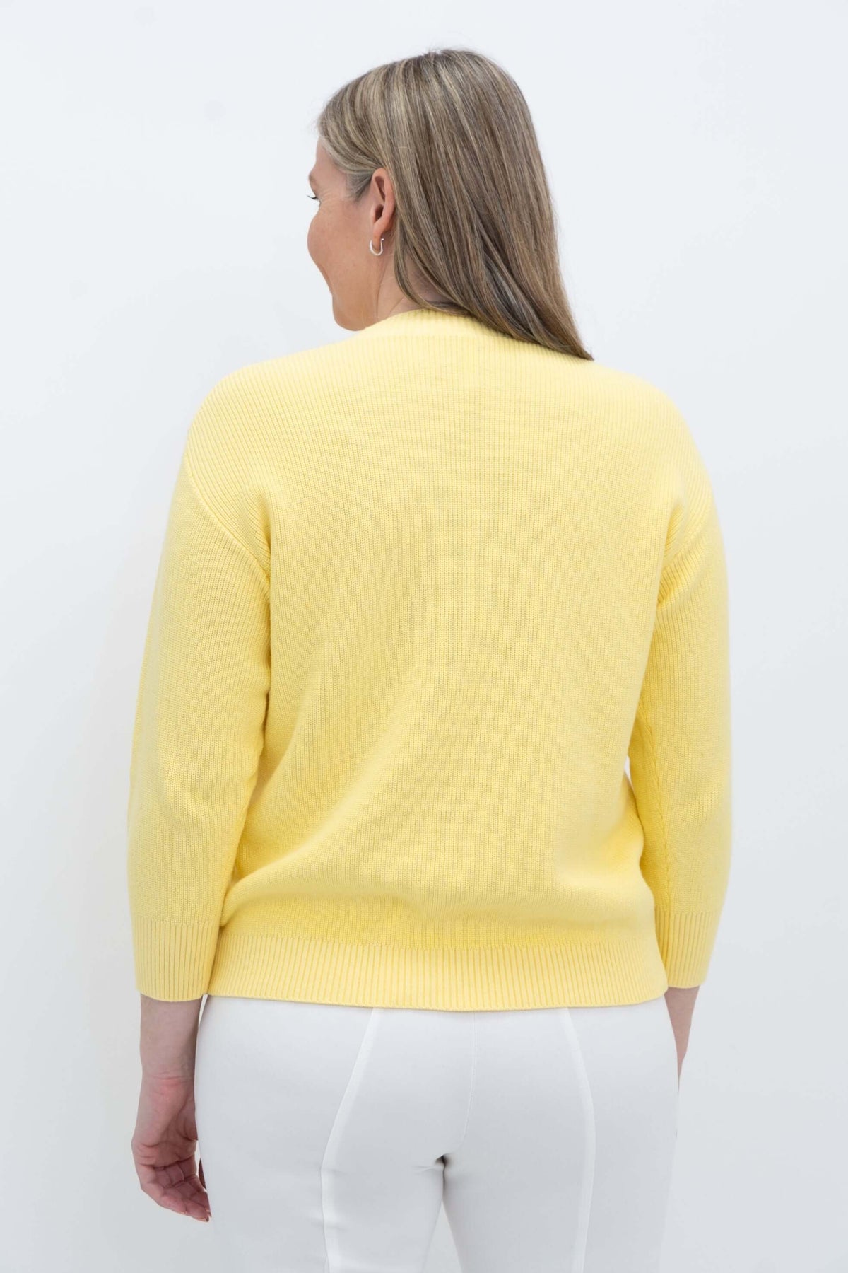 Back view of a woman in a yellow cotton sweater showing relaxed drop shoulders