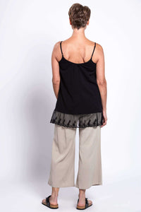 Back view of a woman in a black tank top with lace trim and beige pants