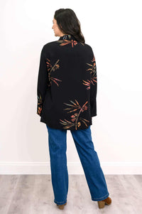 Back view of woman in black smocked floral tunic shirt and blue jeans