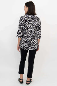 Back view of a woman wearing a black and white Ikat print blouse with 3/4 sleeves